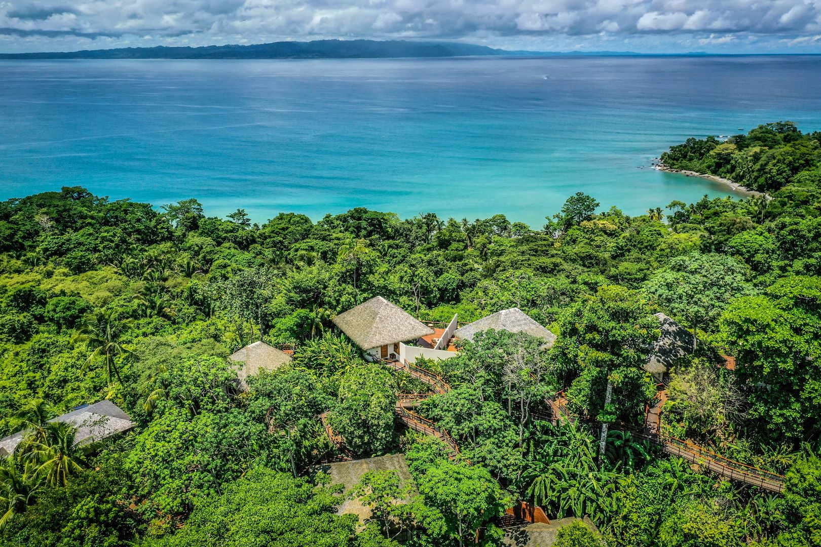 Aerial view of Lapa Rios Lodge surrounded by rainforest with a stunning ocean backdrop.
